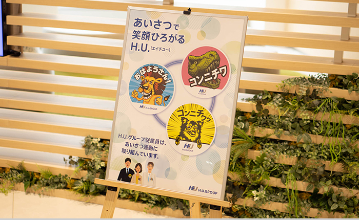 「コミュニケーション方針バッジ」あいさつで笑顔広がるH.U.（エイチユー）H.U.グループ従業員は、あいさつ運動に取り組んでいます。